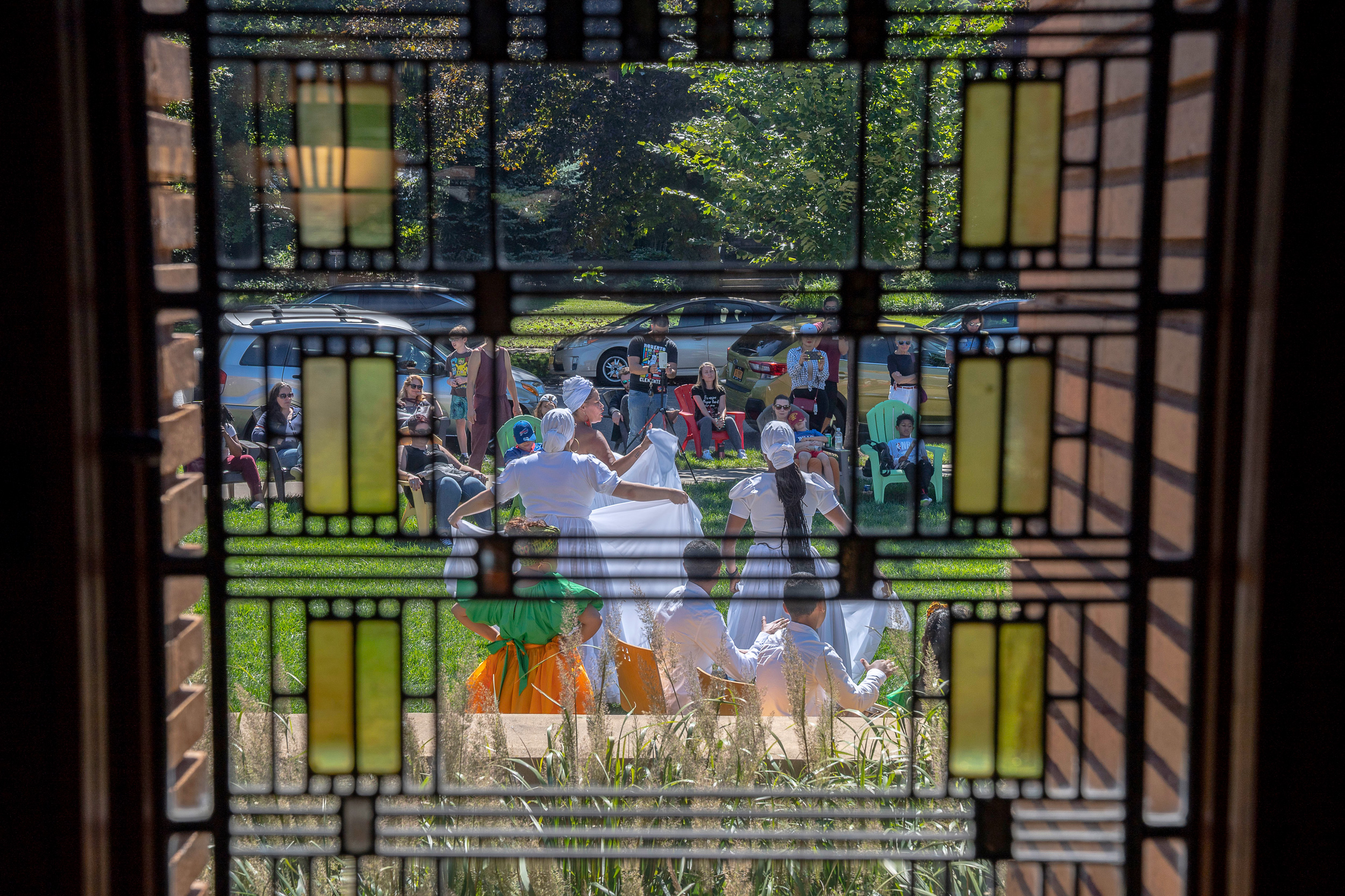 group of people gathered on the lawn watching while hispanic women in long white dresses perform latin dance